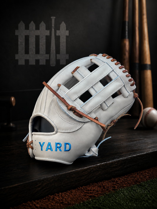 Baseball glove with 'YARD' branding on a wooden surface with baseball bats in the background.